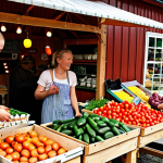 **

A vibrant farmers market in the Swedish countryside. Focus on fresh, locally grown produce displayed on wooden stalls. Happy customers interact with the farmers, who are showcasing organic vegetables and homemade crafts. Include a "Gårdsbutik" sign and a sense of community. The scene should evoke a feeling of "hållbar konsumtion" (sustainable consumption).

**